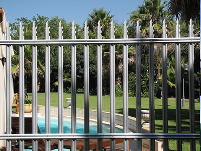 Gray steel palisade fence around the swimming pool, one pointed top type with two notches.